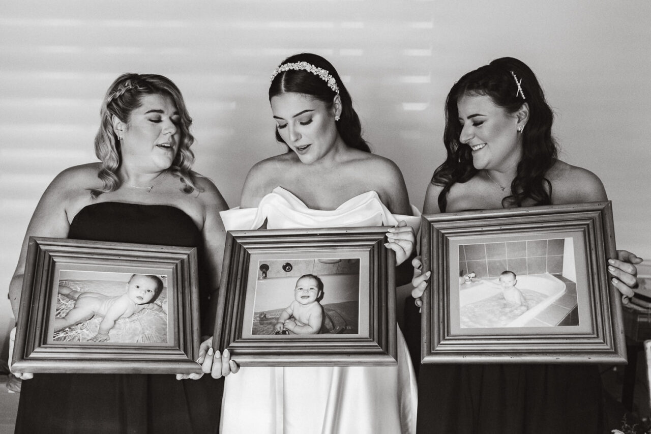 Bride and bridesmaids holding photos of themselves when they were babies.